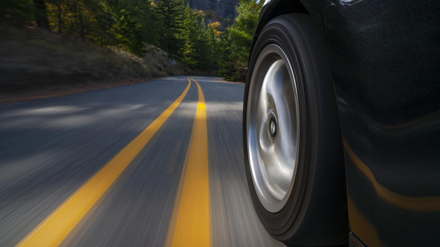 side view of car wheel on a road near forests